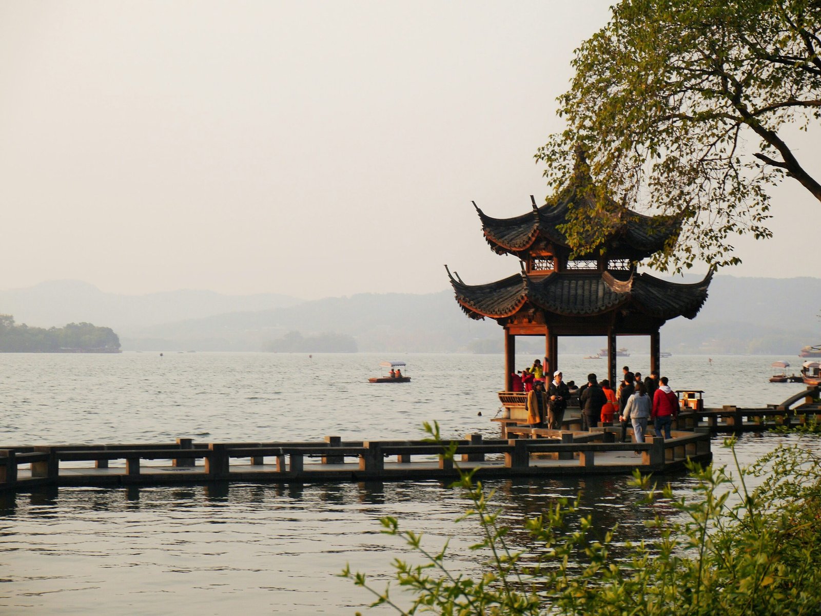 Västra sjön i Hangzhou med paviljong och kullar i morgonljus